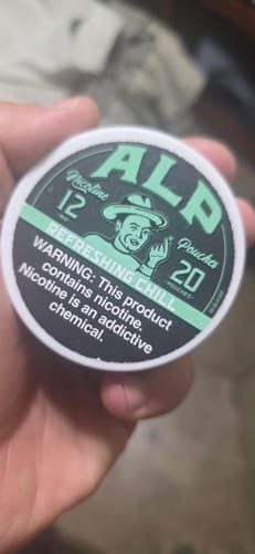 Customer's hand holding a round tin of Refreshing Chill Nicotine Pouches, showing the lid.