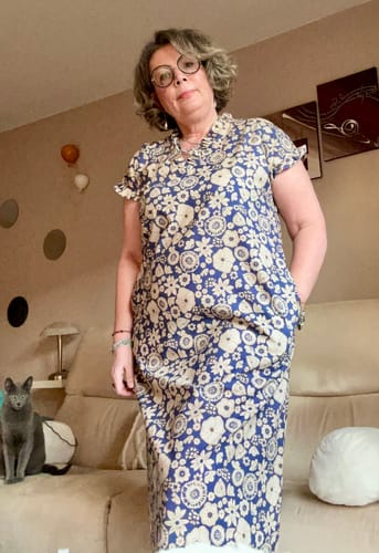 Une cliente portant la robe Acacia à imprimé fleuri bleu, montrant sa coupe ample et fluide.