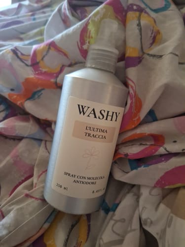 Un cliente mostra lo spray antiodore L'Ultima Traccia appoggiato su un lenzuolo colorato.