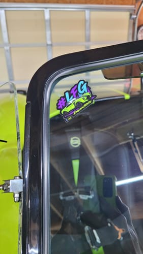 Customer's custom cut to shape sticker with a colorful car graphic, applied to the corner of a vehicle's window.