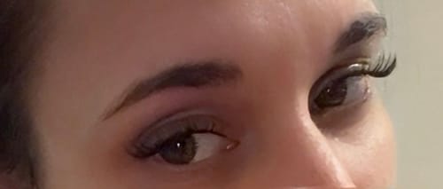 Nahaufnahme der Augen einer Kundin, die mit dem schwarzen Top Coat behandelte Wimpernextensions trägt.
