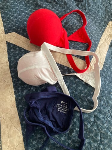Customer's three-pack of Modal thongs in red, white, and navy blue laid out on a bed.