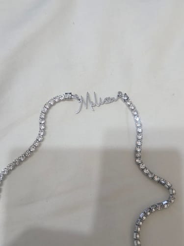 Customer's silver Signature Name Tennis Necklace with the name 'Melissa' laid on a white surface.