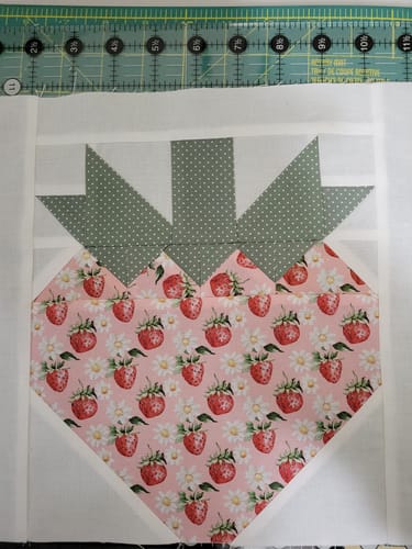 Reviewer shows a precisely sewn strawberry quilt block from the Strawberry Fields Sew-Ready Precut Quilt Kit.