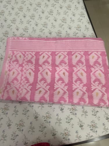 Customer's folded pink SurTara Dhakai Jamdani Saree, showing its detailed white and gold woven pattern.