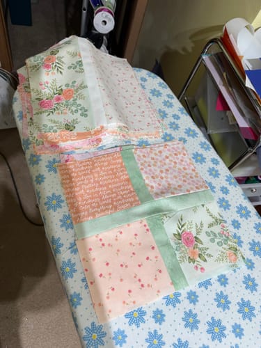 Customer's Apple Cider Quilt Kit pieces, featuring beautiful floral fabric, being assembled on an ironing board.