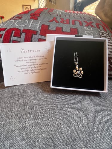 Cliente mostrando el Collar Huella Encantadora en su bonita caja de regalo, junto a una tarjeta.