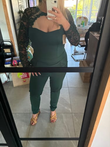Cliente portant la combinaison verte CECILE, montrant la coupe ajustée du vêtement et ses manches longues en dentelle.