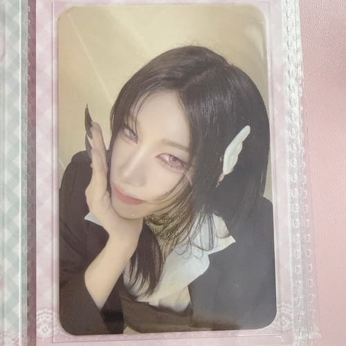 Customer's XLOV "I,God" photocard showing a person with dark hair and pointed ears, held in a plastic binder sleeve.