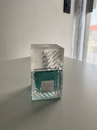 El perfume Khamrah Waha Lattafa de un cliente, con su botella de vidrio cuadrada sobre una mesa blanca.