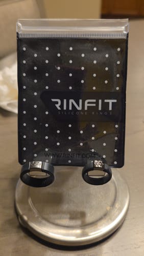 Customer's two black MetalInfinity silicone rings with metal details displayed on their original packaging.