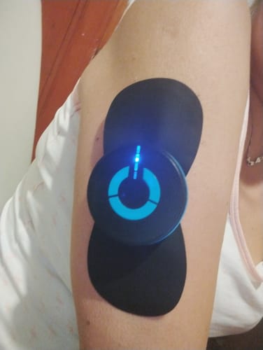Vásárló karján a bekapcsolt Vital Pulser Pro EMS izomstimuláló masszírozó készülék.