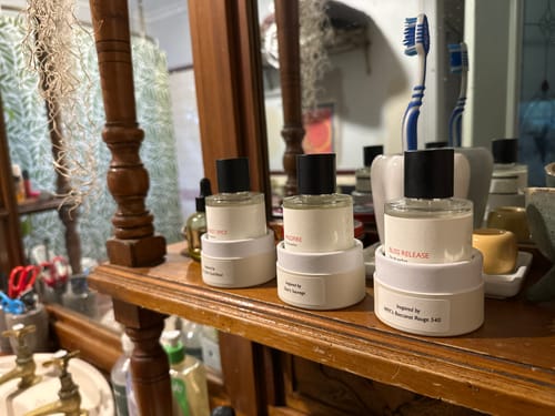 Customer's Forest Spice perfume bottle on a wooden shelf next to two other perfumes.