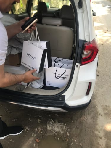 Customer placing shopping bags containing The Royal oud Collection into the trunk of a car.