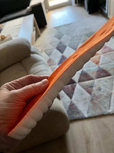Vásárló kezében tartja az AIRFIT ULTRA talpbetétet, amelynek narancssárga a felső, és fehér, hullámos az alsó része.
