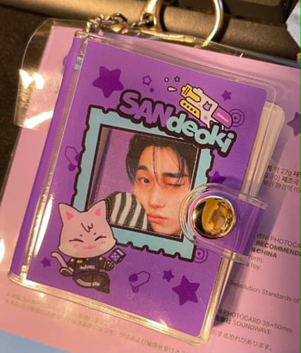 Customer's purple Sandeoki mini album keyring, showing the cover with a cartoon cat and a photocard of a person.