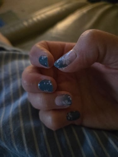 Customer's hand showing Holy Gels nail stickers with a blue and white floral design, showing significant nail growth.