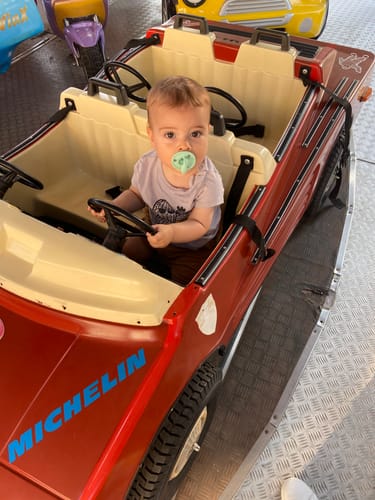 Cliente muestra a su bebé en un coche de juguete con el chupete clásico verde de Nenina & Co.