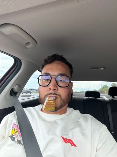 Customer in a car holding a packet of SuperCharged Honey in their mouth, ready to eat.