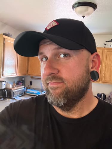 Reviewer wearing the black Big Structured Baseball Cap, showing its deep fit from a side angle.