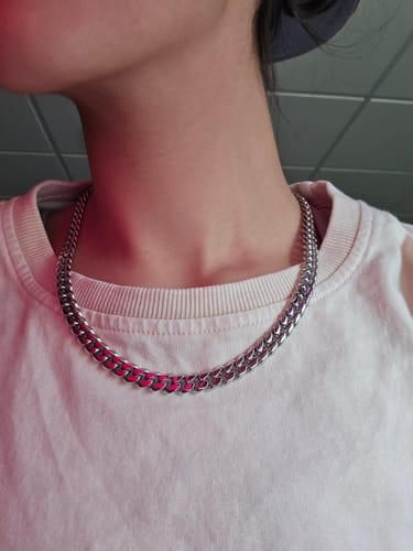 Close-up of a reviewer wearing the silver CUBAN CHAIN around their neck against a white t-shirt.