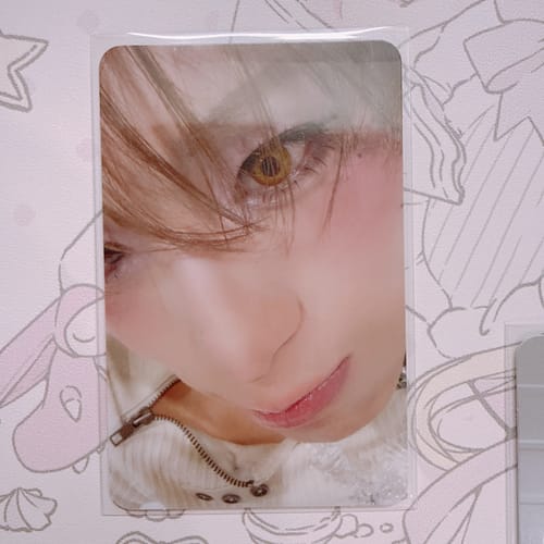 Close-up of a customer's XLOV "I,God" official photocard held up in a protective clear sleeve.