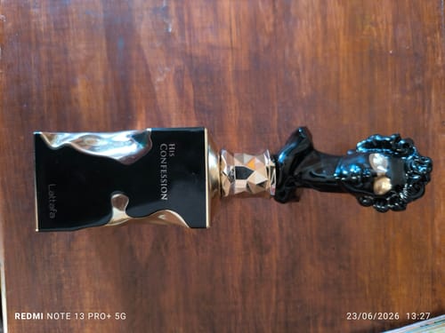 Reseñador muestra el perfume Lattafa His Confession. La elegante botella negra tiene una tapa ornamentada en forma de busto.