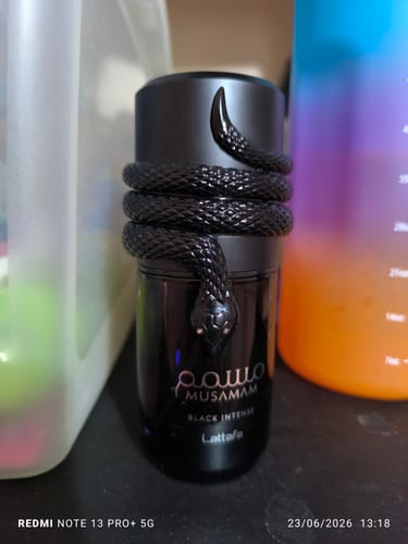 Un cliente muestra el frasco negro del perfume Lattafa Musamam Black Intense con su distintivo diseño de serpiente.