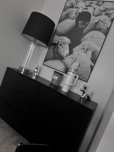 Customer's framed 'Built Different' art print hanging on a wall above a black dresser in a room.