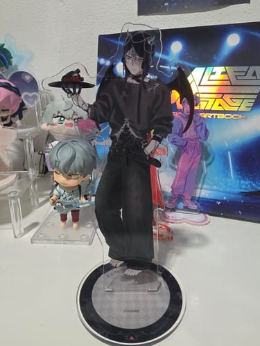 Customer's large Alien Stage acrylic stand of the character Till, displayed on a desk with other merchandise.