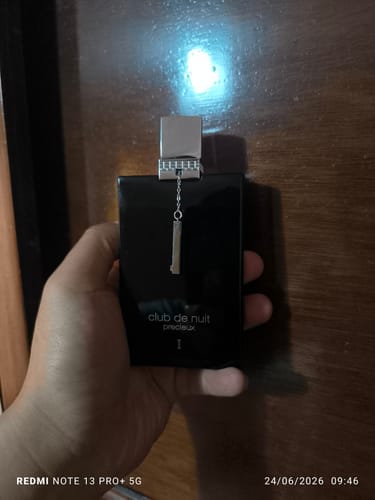 Un cliente sostiene el frasco negro del perfume Club de Nuit Precieux en su mano.