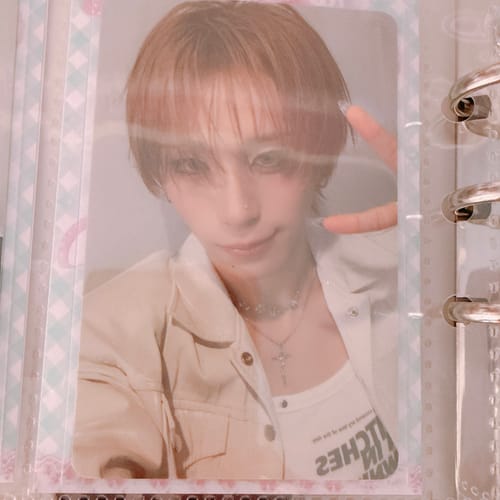 Reviewer's XLOV "I,God" photocard of a person with short hair making a peace sign, placed in a protective binder page.