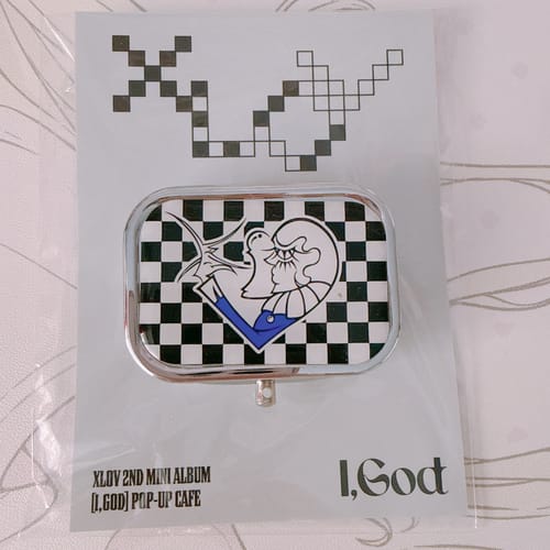 Customer's XLOV 'I,God' pop-up store case in its original packaging, featuring a checkered illustration.
