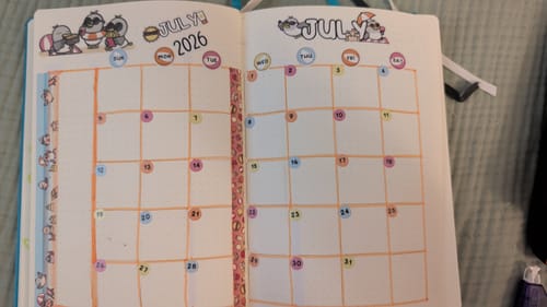 Reviewer's journal showing a decorated July calendar spread using stickers and washi tape from the Ultimate Subscription.