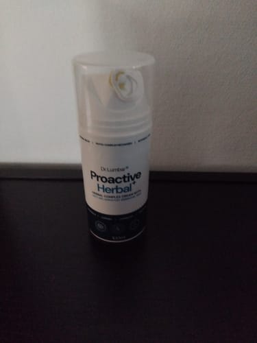 Vásárló Proactive Herbal+ krémje egy fehér, pumpás flakonban egy sötét felületen.