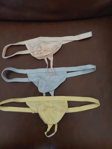 Reviewer's three Modal 0in Thongs in yellow, grey, and peach laid out on a brown surface.