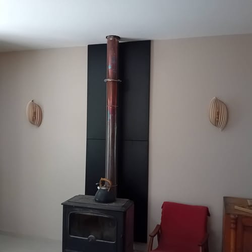 Avis d'un client : deux appliques murales Assia en bois clair installées de chaque côté d'un poêle.