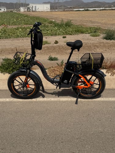 Customer's customized black Vakole Y20 Pro e-bike with orange accents, shown from the side while parked on a paved road.