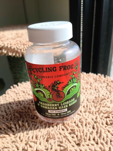 Reviewer's nearly empty bottle of Cranberry Limeade Rosin Gummies sitting on a textured surface in the sun.