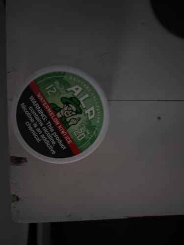 A customer's can of Drifters Watermelon Kiwi Ice Nicotine Pouches shown resting on a white wooden surface.