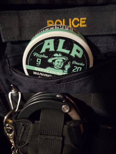Customer's can of Chilled Mint Nicotine Pouches sticking out of a pocket on a black police vest.