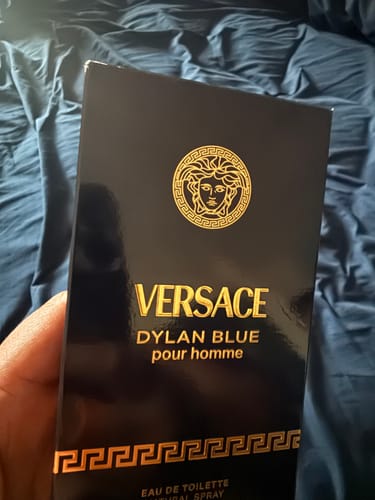 Primer plano de un cliente sosteniendo la caja del perfume Versace Dylan Blue pour homme.