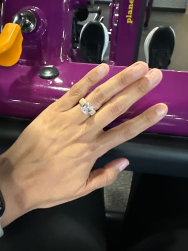 Reviewer's hand wearing the Silicone Ring with a large emerald-cut stone, shown at the gym.