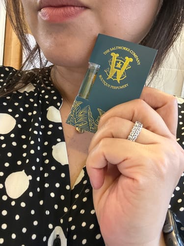 Customer holding a sample vial of Copacabana perfume against its dark green card.