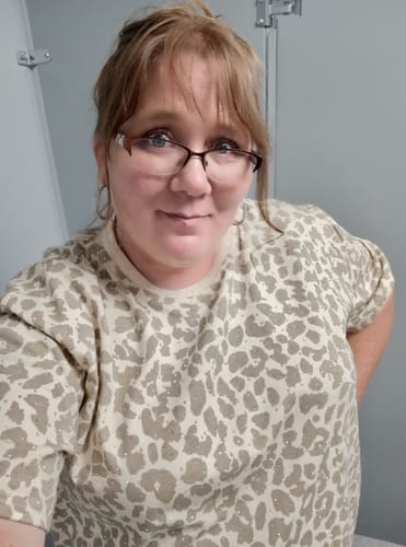 Reviewer wearing the taupe leopard print short sleeve top, which features small, sparkly rhinestones.