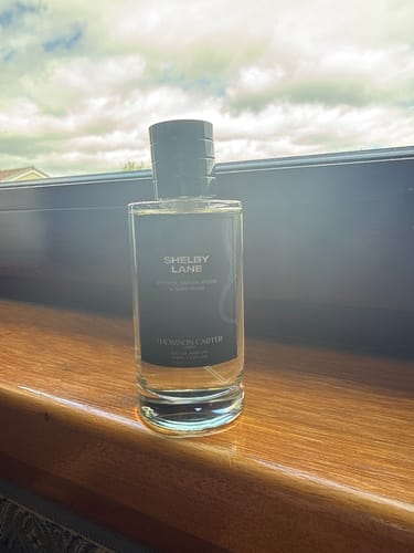 Customer's Shelby Lane Eau de Parfum bottle placed on a wooden windowsill.