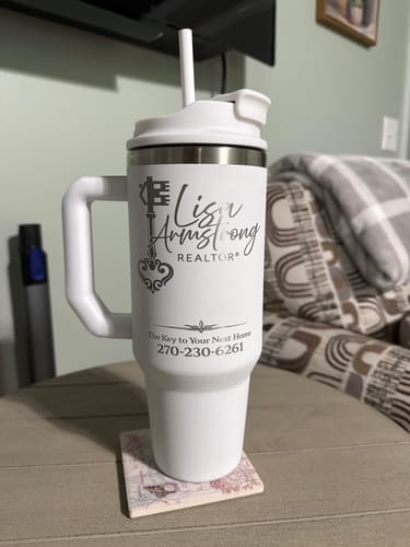 Customer's white Thicc Buddy 40oz mug, personalized with a realtor's logo, sitting on a coaster on a table.