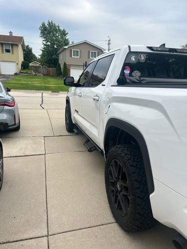 Reviewer's white truck parked in a driveway, showing the wider stance from installed 1.5 inch wheel spacers.