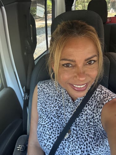 Reviewer smiling in a car, showing clear skin after using the Micro Infusion System.