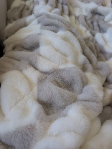 Close-up of the reviewer's plush Hugs Diamond Ancient Scroll Blanket, showing the tan and cream pattern.
